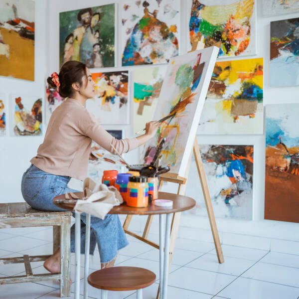 Female artist painting on canvas doing some art projects on her studio workshop